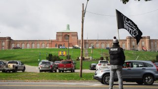 A protester waves a “Black Lives Matter” flag across the street during the demonstration. Representatives from various organizations including Free the People Roc and HALT (Humane Alternatives to Long-term) travelled to Elmira Correctional Facility from across the state to protest the conditions faced by inmates during the COVID-19 pandemic. The state prison in Elmira, N.Y., has seen a rash of coronavirus cases.